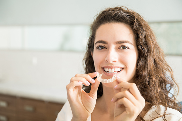 A woman is holding her clear aligners in her hands.
