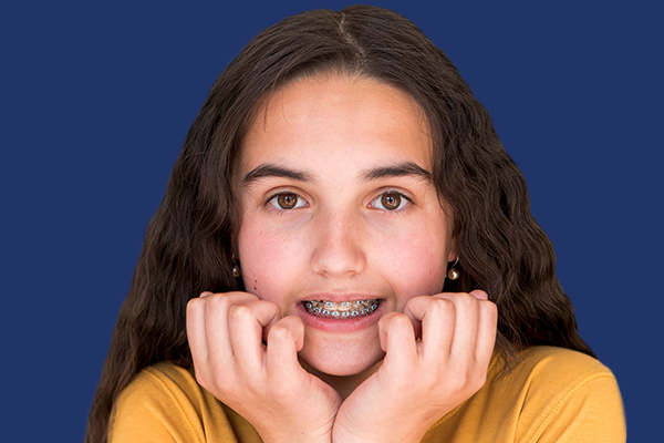 A young girl with braces on her face, demonstrating the disadvantages of traditional braces.