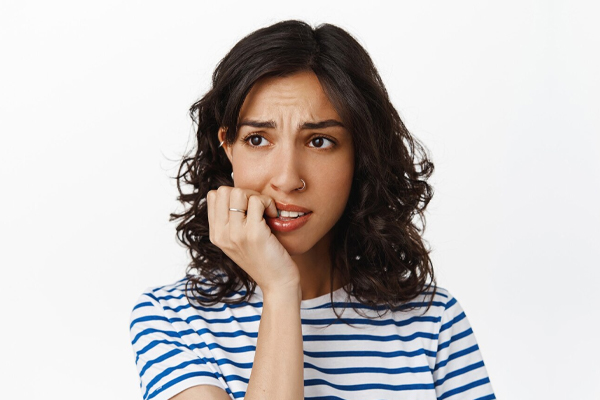 A young woman is holding her hand over her mouth, wondering if clear aligners are painful.