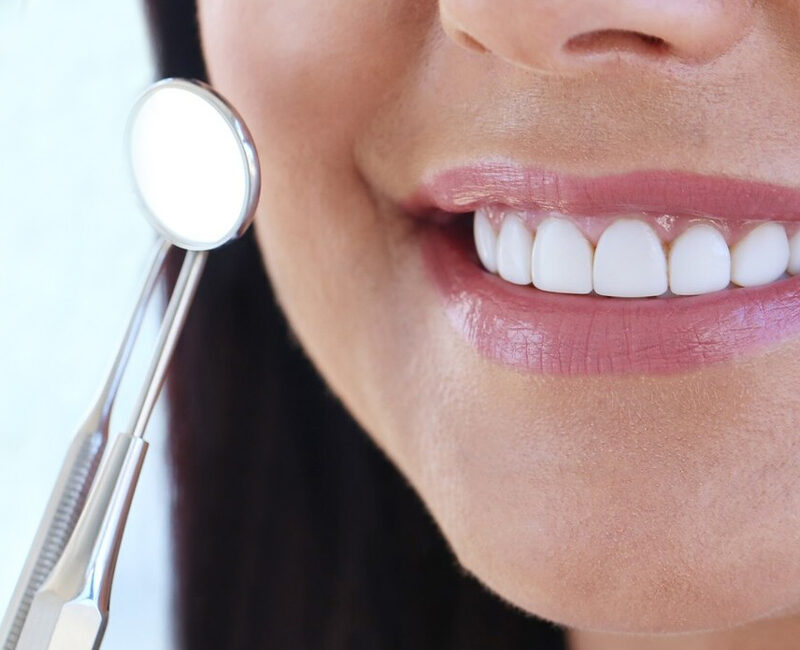 A woman is holding a dental mouth mirror.