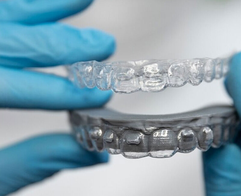 A person is holding a clean clear aligner trays.
