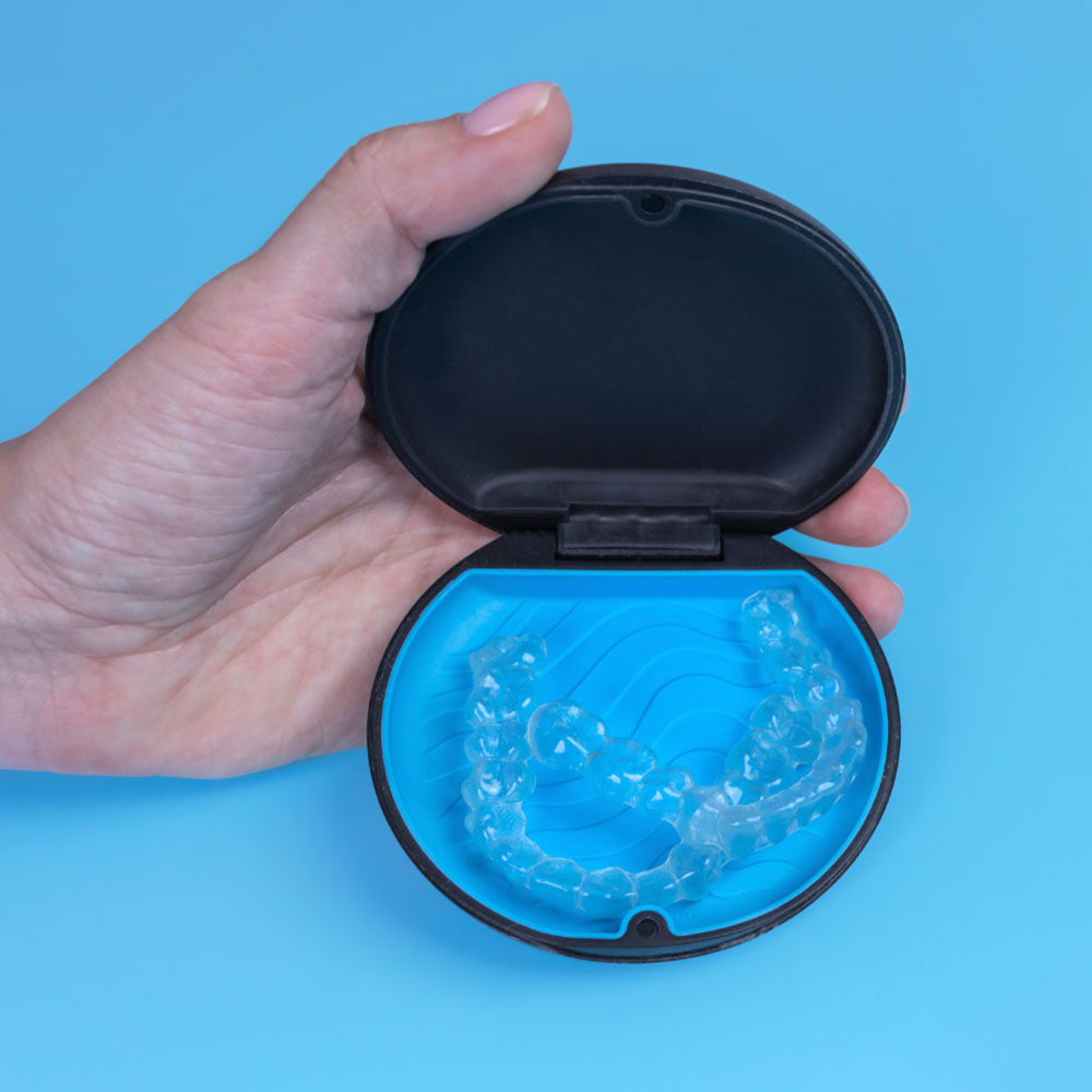A person holding a invisible braces case on a blue background