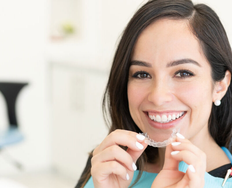 A woman smiles while sitting in a dentist's chair.