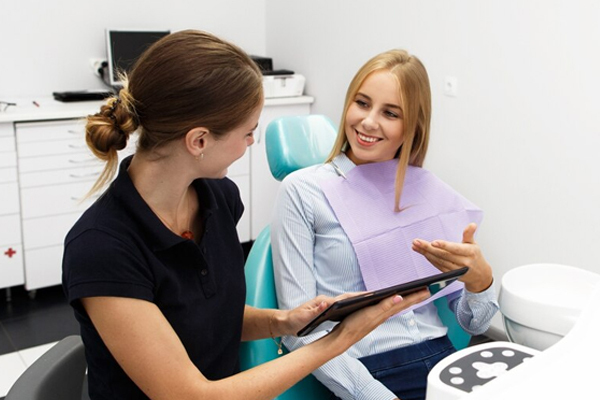 Dental professional discussing teeth straightening surgery with a smiling patient in a clinic.