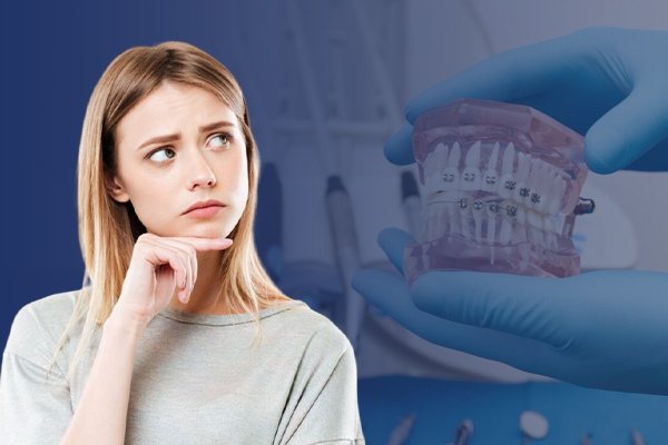A woman appears contemplative against an orthodontic background suggestive of the need to wear braces after teeth straightening surgery.