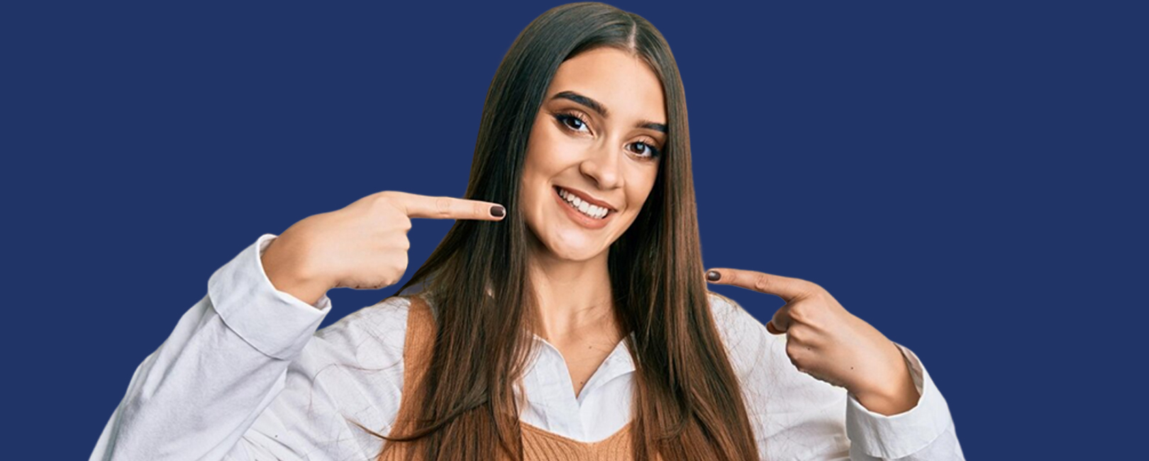 A smiling woman pointing to her clear aligners.