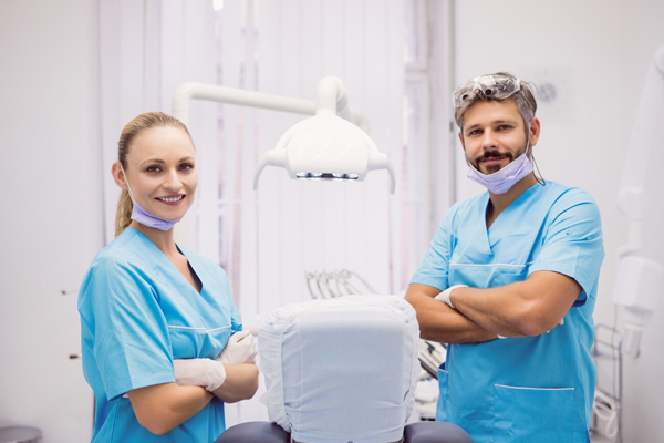 Dental professionals in scrubs standing confidently in a dental clinic, consulting on clear aligners.