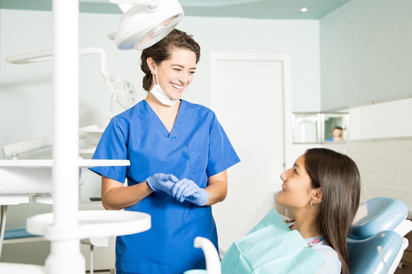 Dental hygienist smiling at a patient in a dental clinic as they discuss clear aligners.